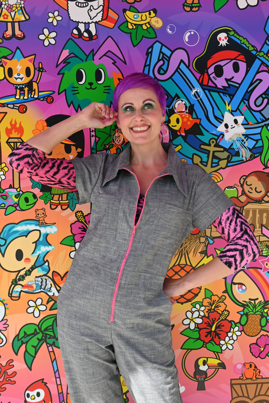 Purple haired model in grey chambray jumpsuit with bright pink zipper