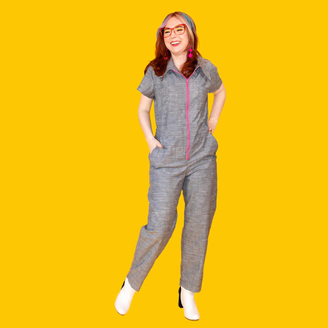 Model in grey blue chambray jumpsuit with bright pink zipper and pockets