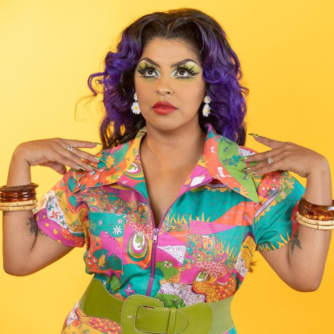 Closeup of purple-haired model in bright colored printed jumpsuit with belt