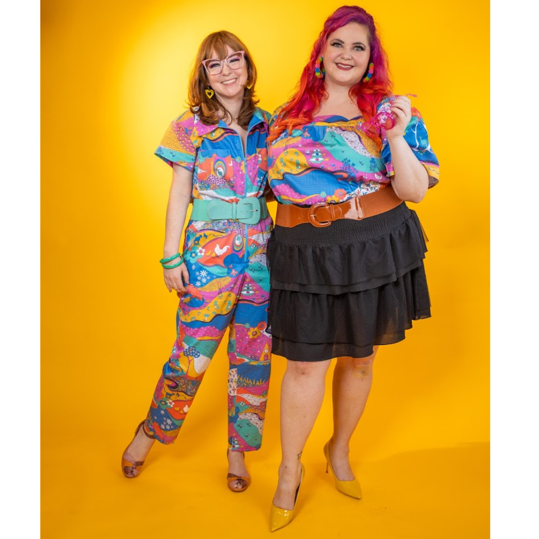 2 models wearing brightly colored printed clothing and smiling