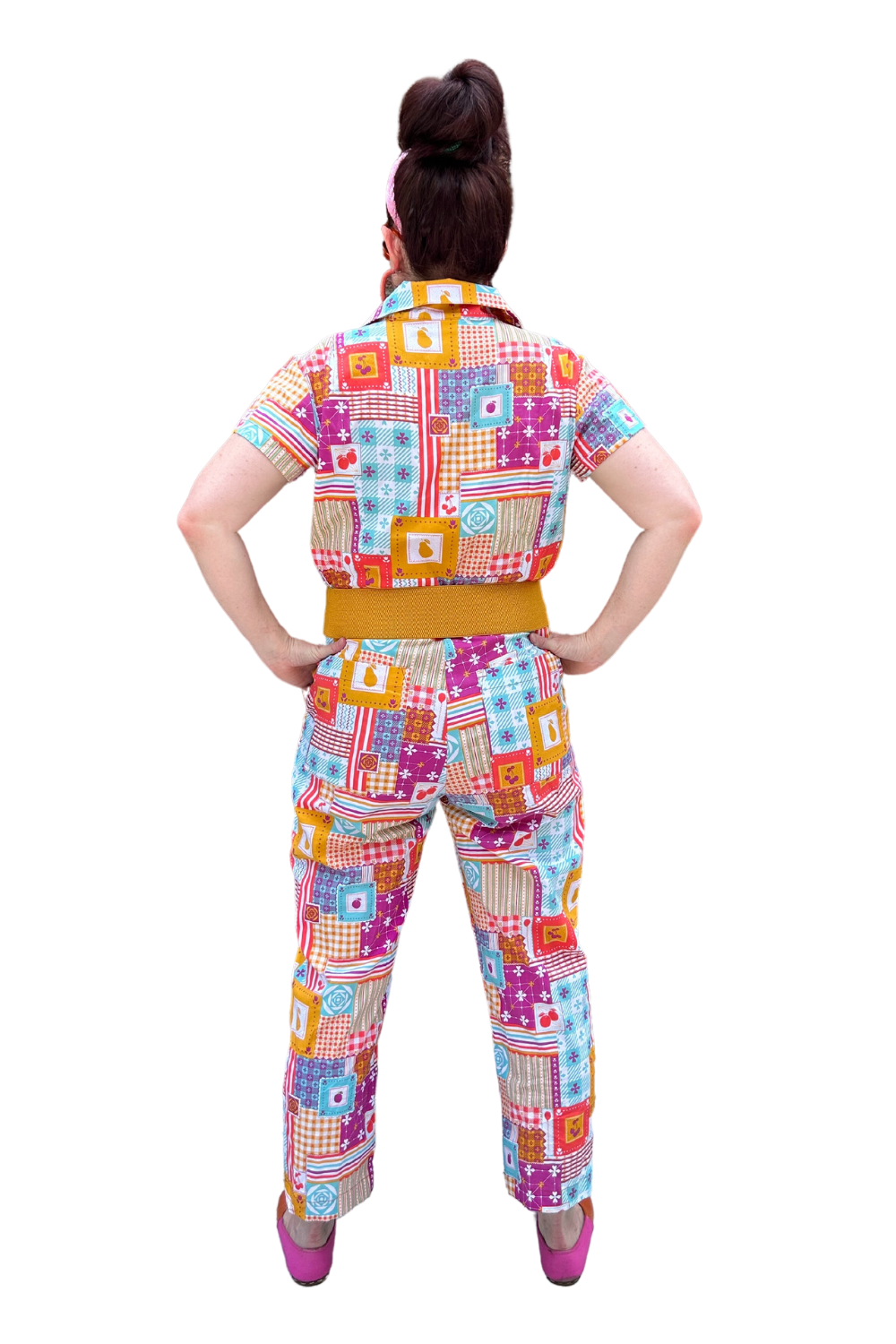Back view of model wearing sunglasses and patchwork print zip-front collared jumpsuit with belt