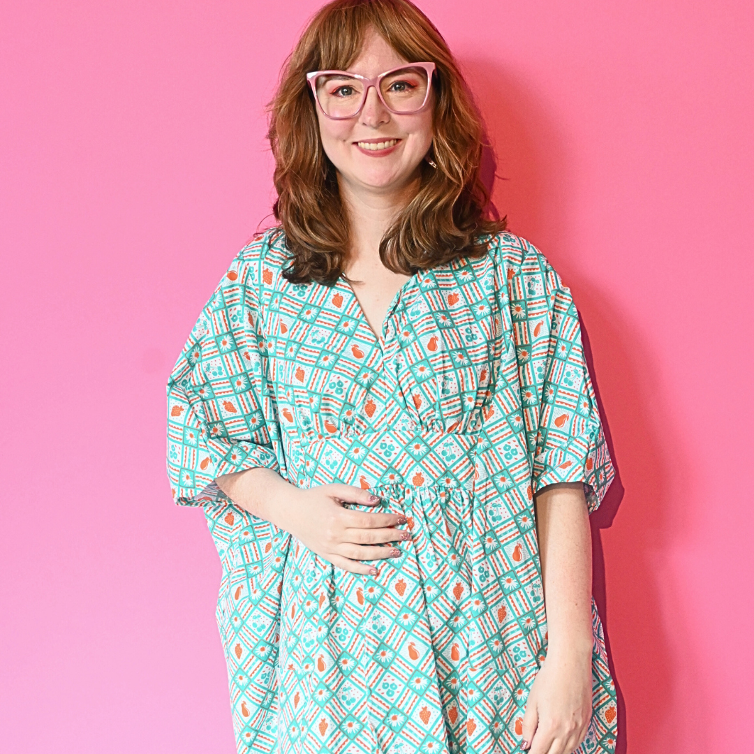 Caftan dress in teal and orange featuring graphic of fruit and flowers