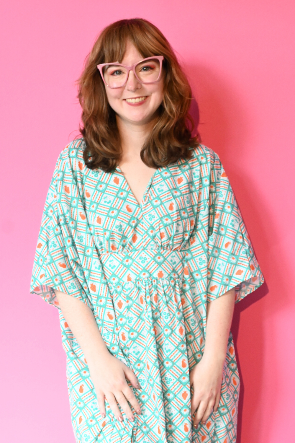 Caftan dress in teal and orange featuring graphic of fruit and flowers