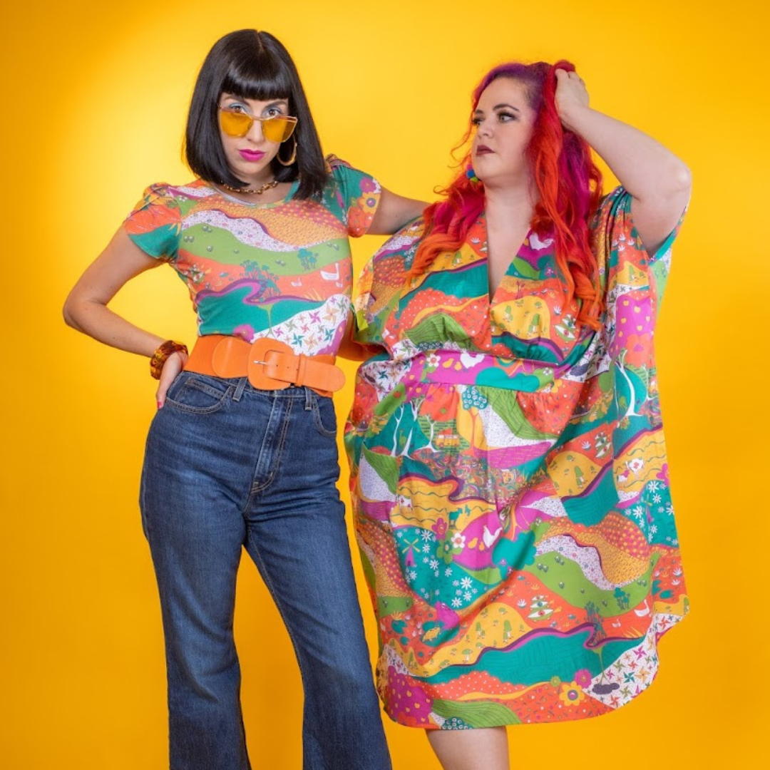 Black-haired model in bright, colorful printed tee with red-haired model in colorful printed caftan