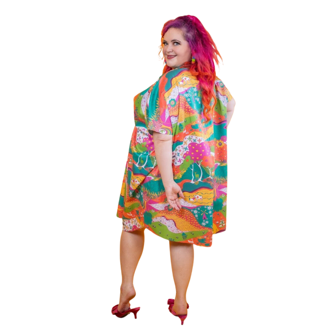 Pink-haired model in bright , colorful caftan, back view