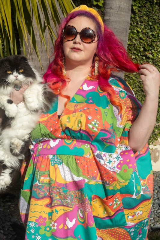 Pink-haired model in sunglasses, bright caftan and holding cat