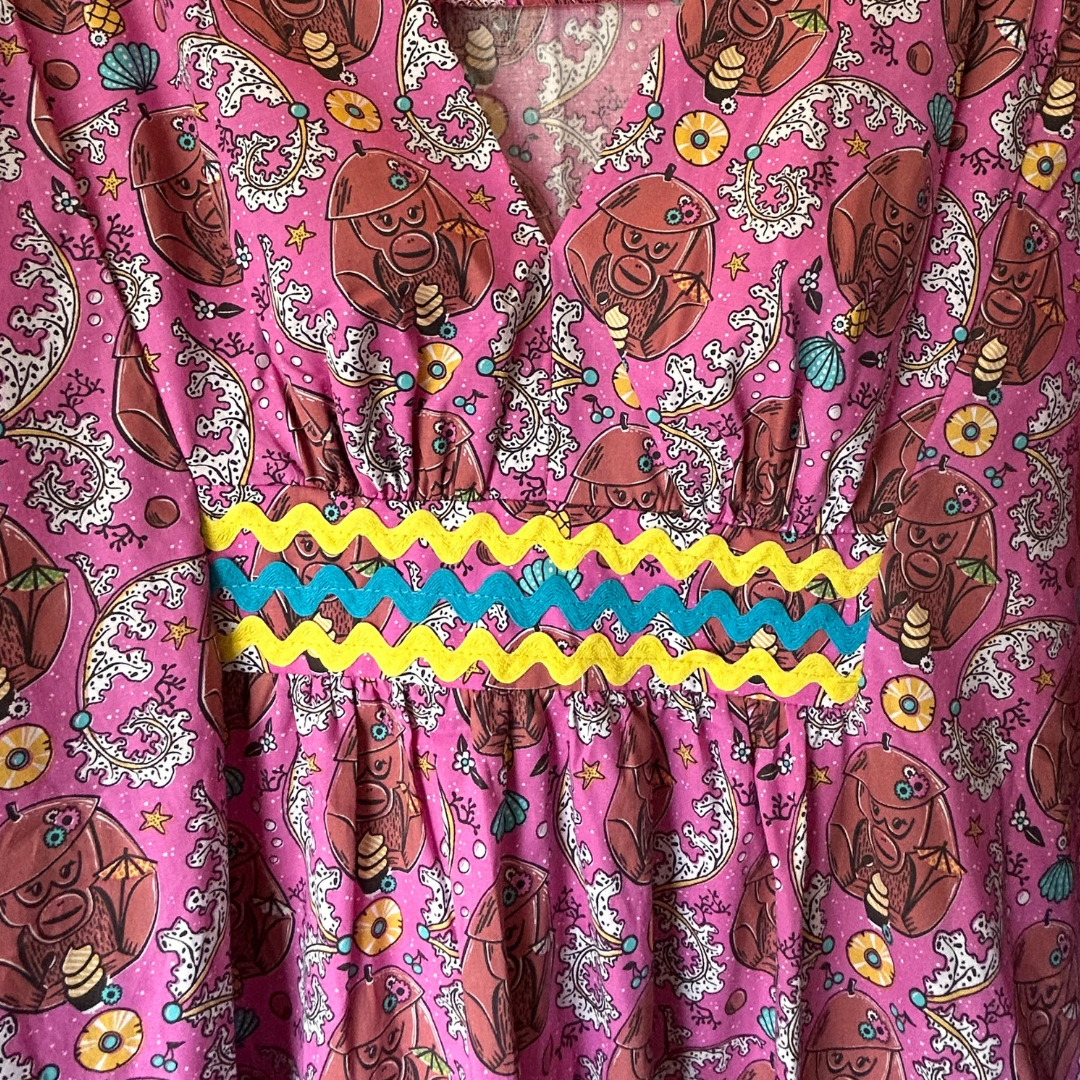 Closeup of magenta monkey print caftan with ricrac trim