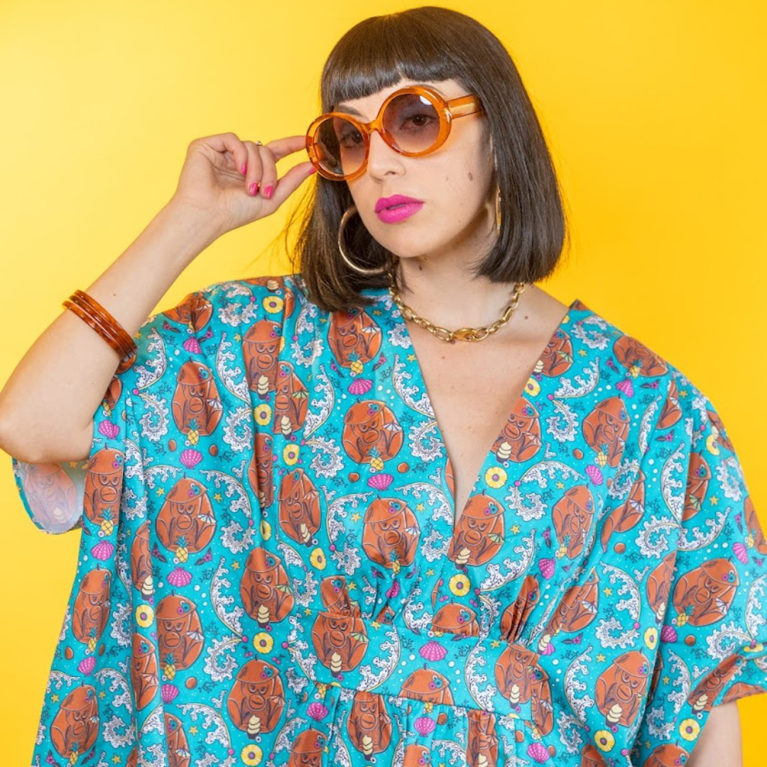 Dark-haired model in big sunglasses and teal monkey print caftan