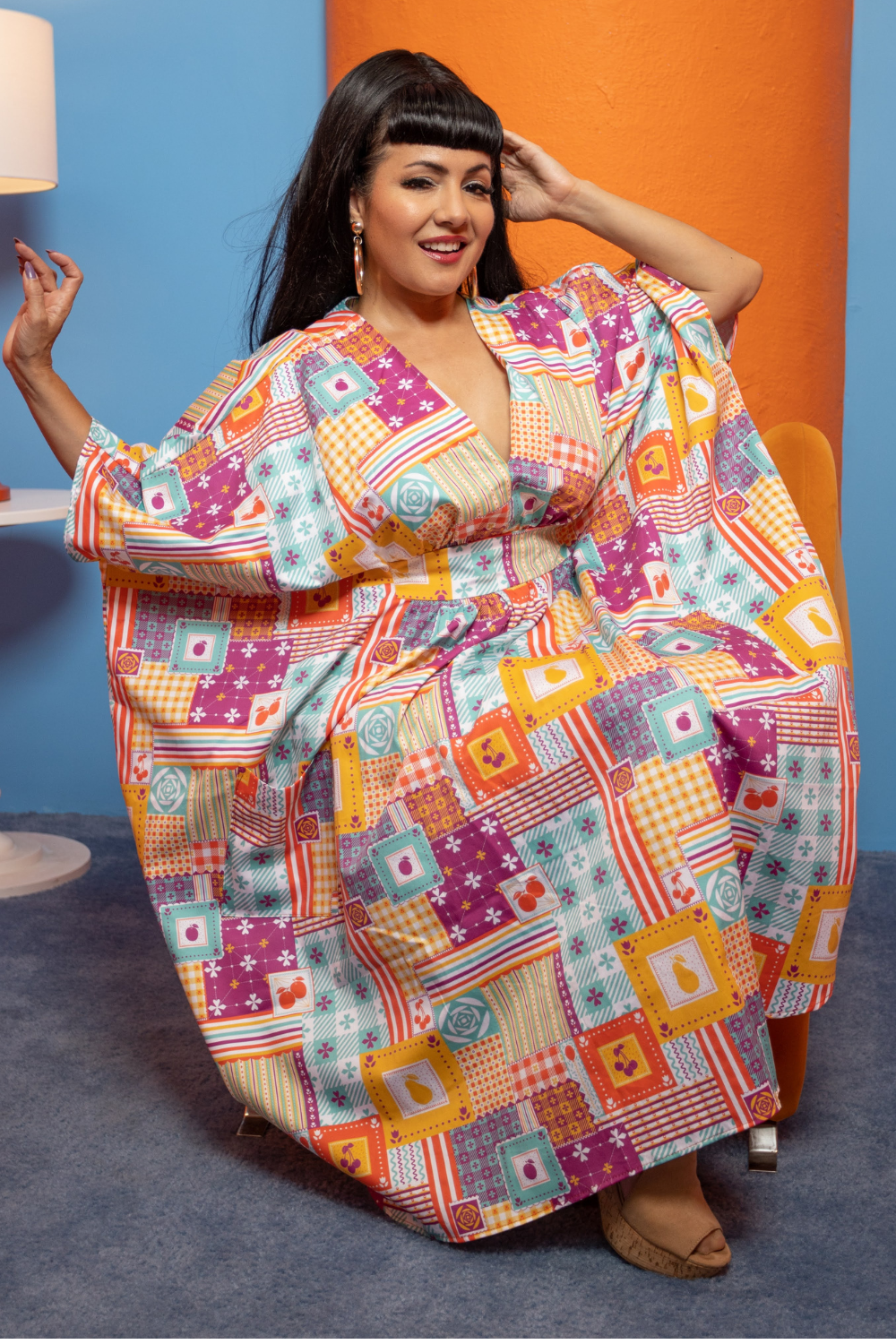 Dark haired model wearing a colorful dress with a patchwork design