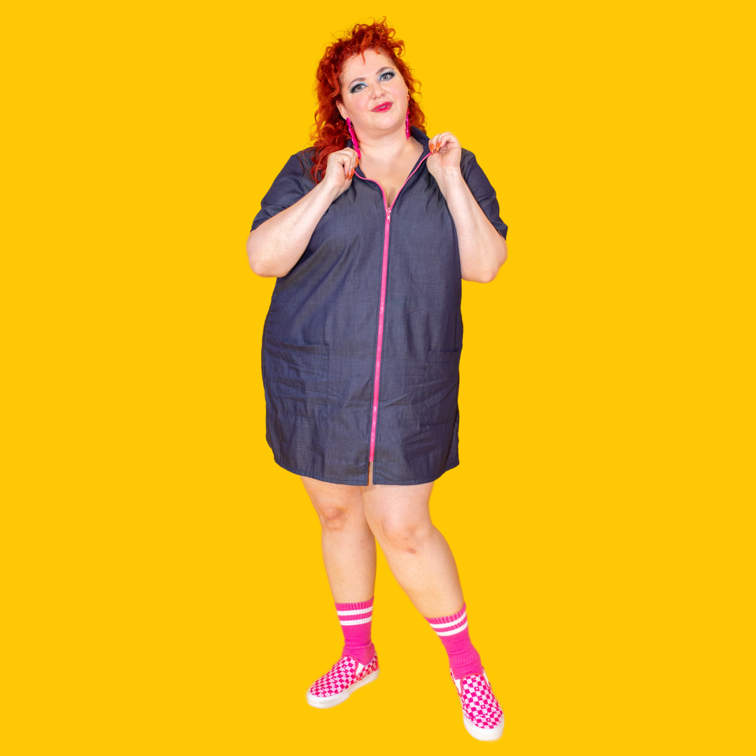 Cute plus-sized model in dark denim dress with bright pink zipper