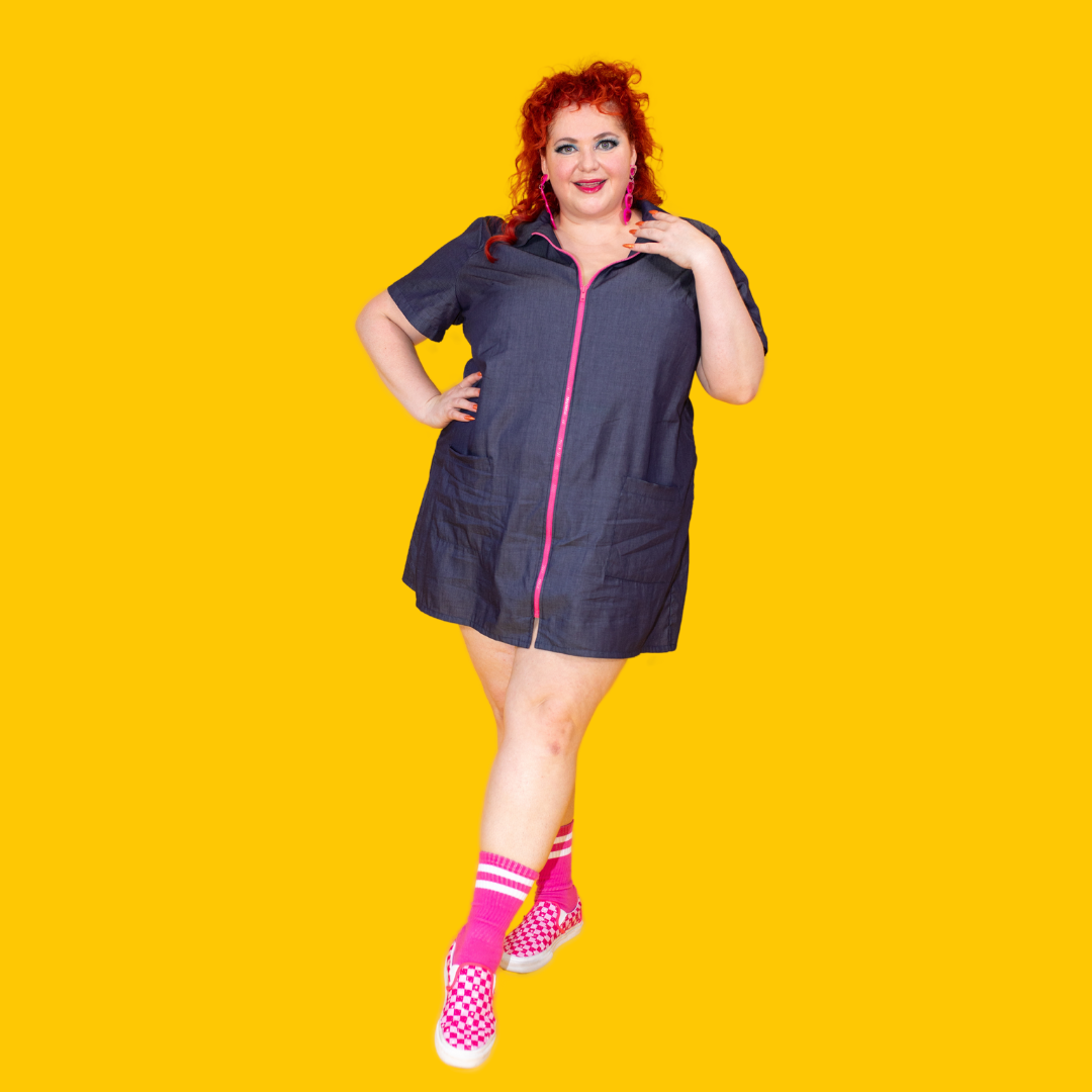 Dark-haired model in denim minidress with bright pink zip and bright pink accessories
