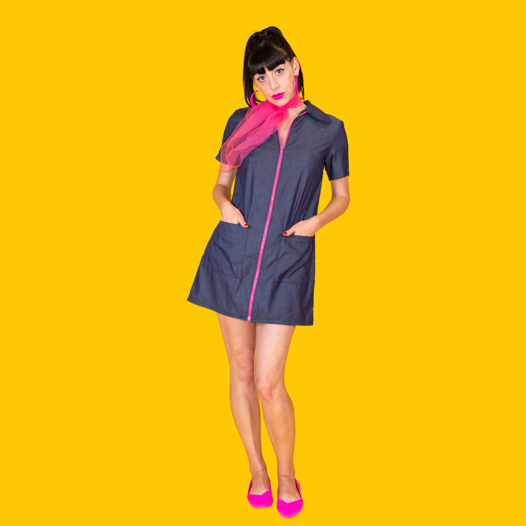 Dark-haired tall model in dark denim minidress with bright pink front zip and Peter Pan collar