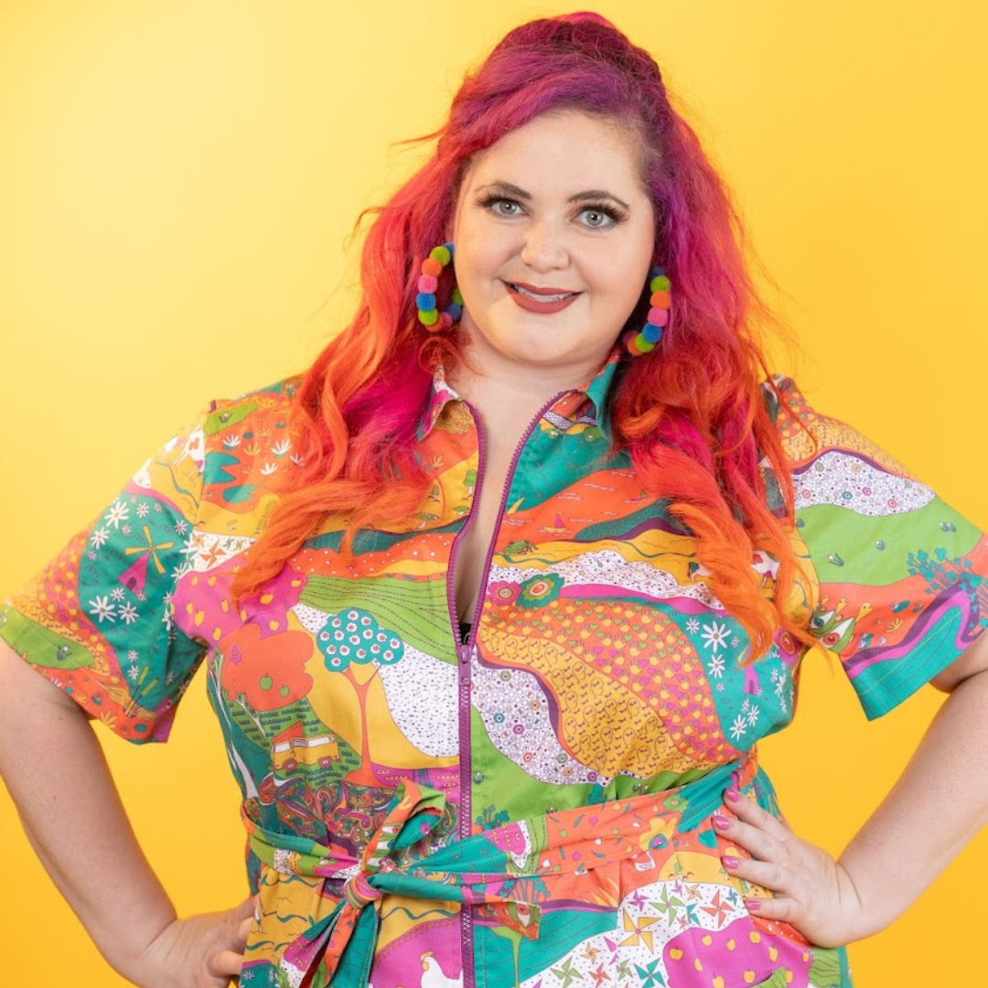 Pink-haired model in brightly colored printed belted minidress