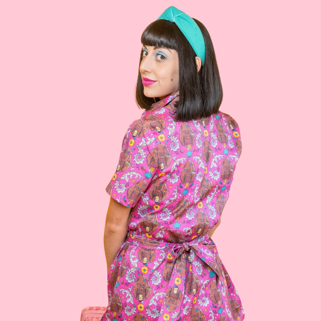 Back view of cute black-haired model in pink dress with tiki monkey print