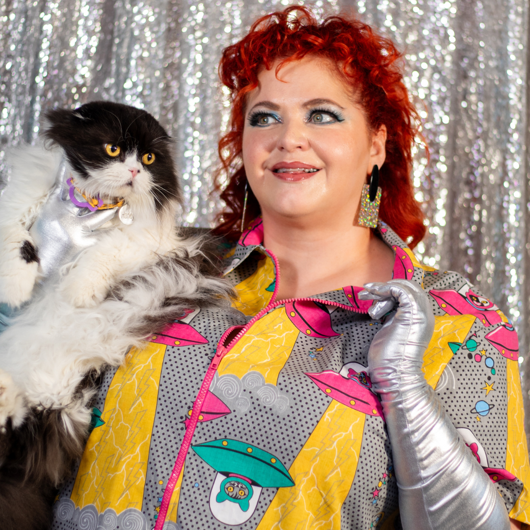 Closeup of model holding cat and wearing dress with space cat print