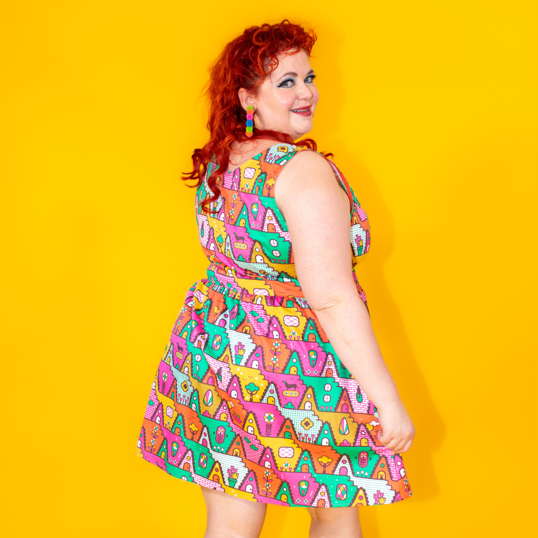 Back view of red-haired model wearing bold-colored geometric print dress