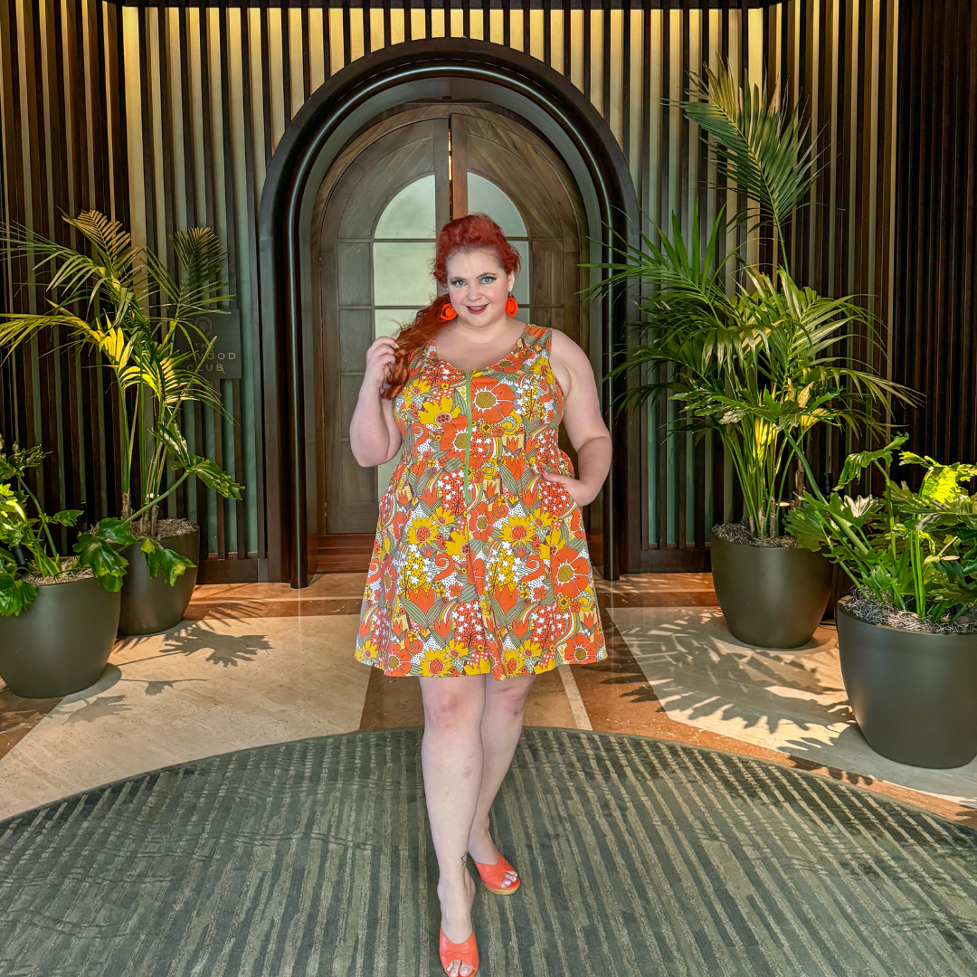Red-haired model in bright floral dress standing in rounded archway