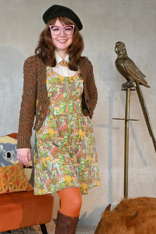 Cute brown-haired girl wearing mushroom print layered with cute cardigan, tights, boots and a beret in living room