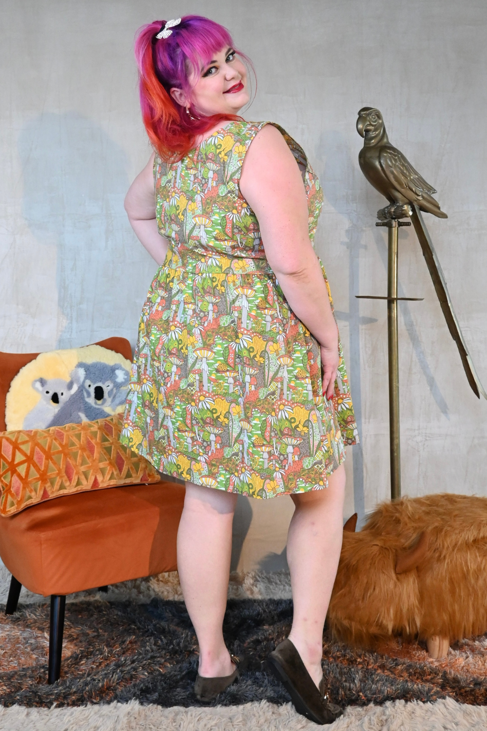 Back view of pink-haired model in psychedelic mushroom-print zip-front dress