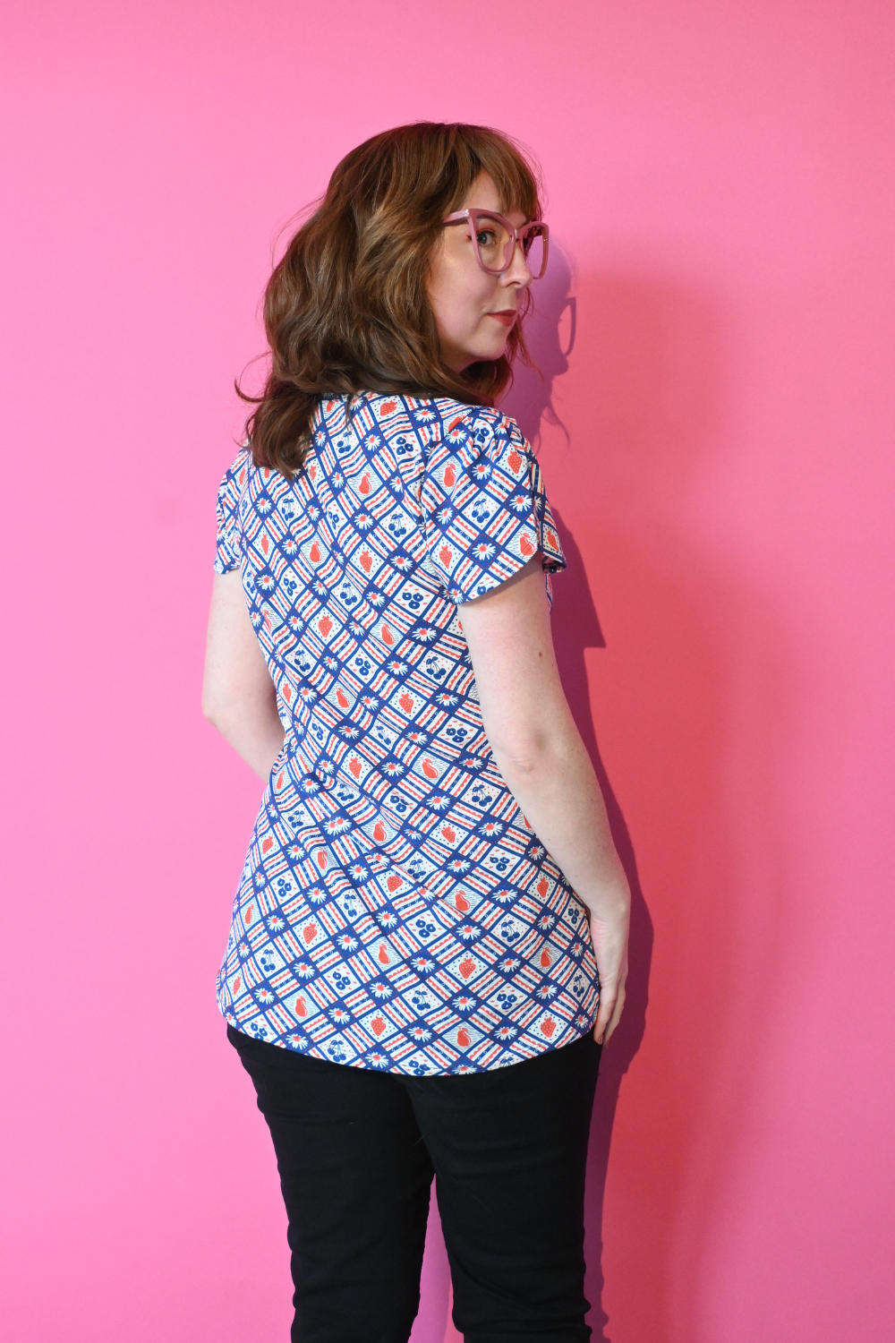 Girl with glasses in red and navy fruit and gingham print tee , back view