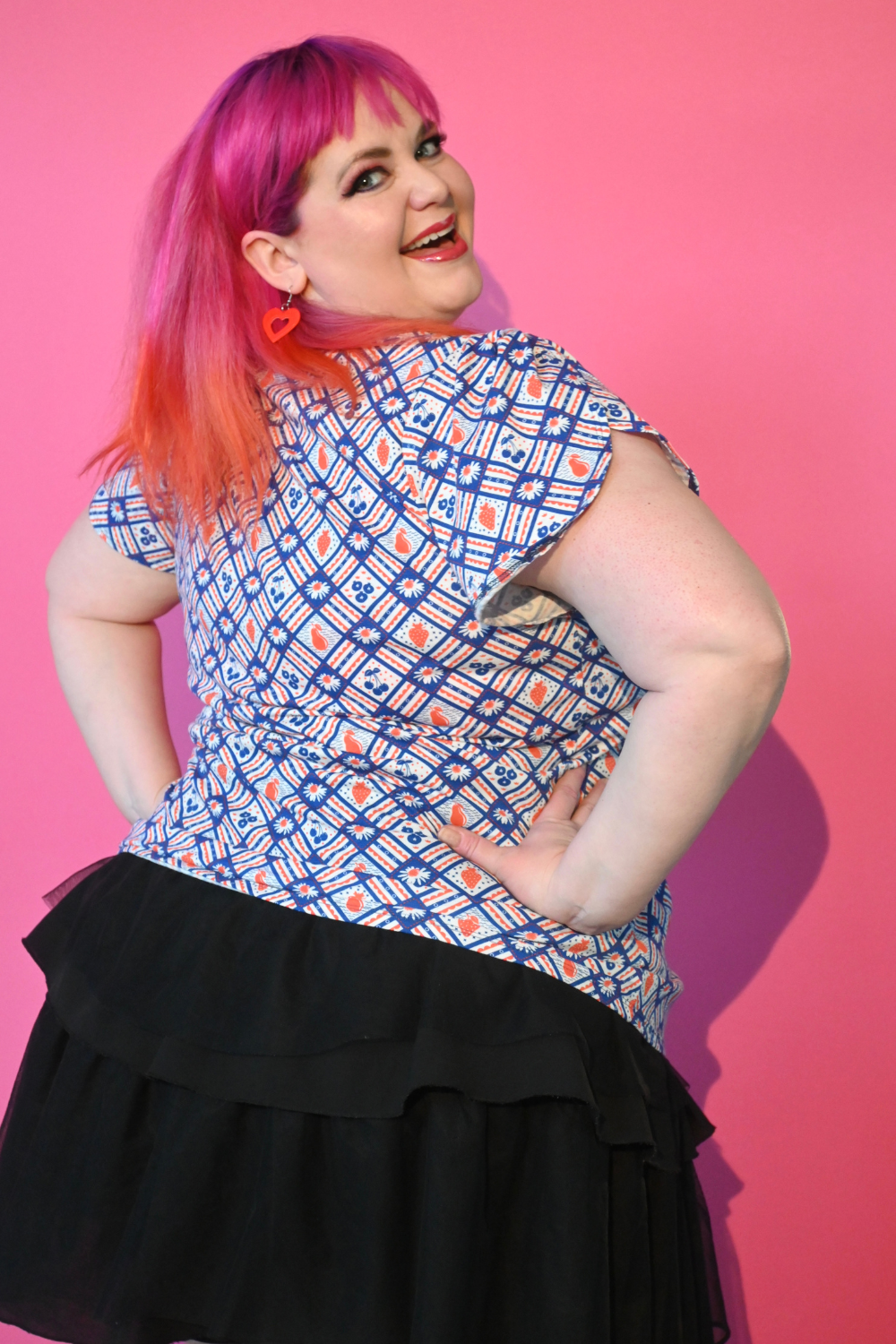 Back view of pink-haired model in red and blue fruit print tee