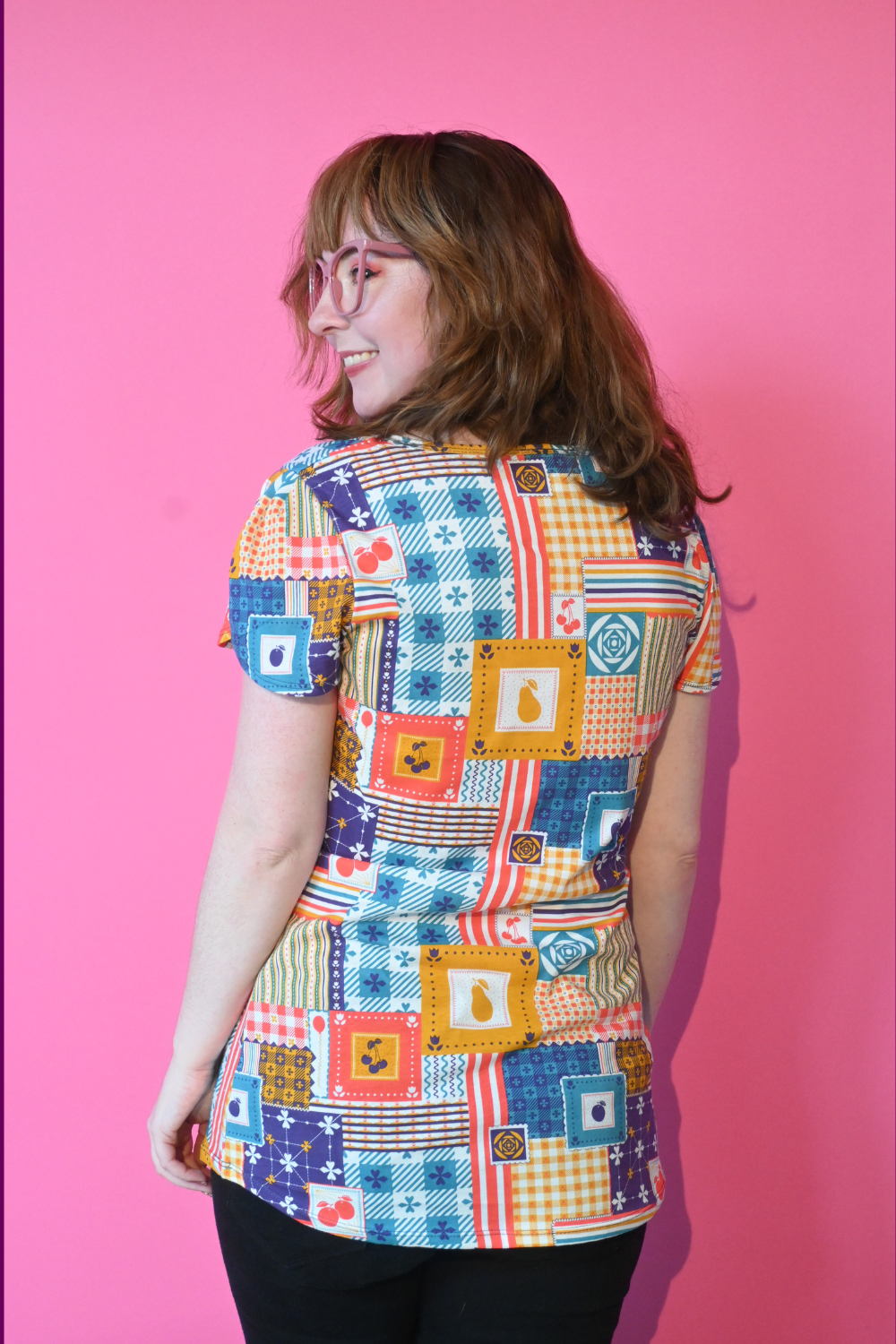 Back view of brown-haired model in patchwork print tee
