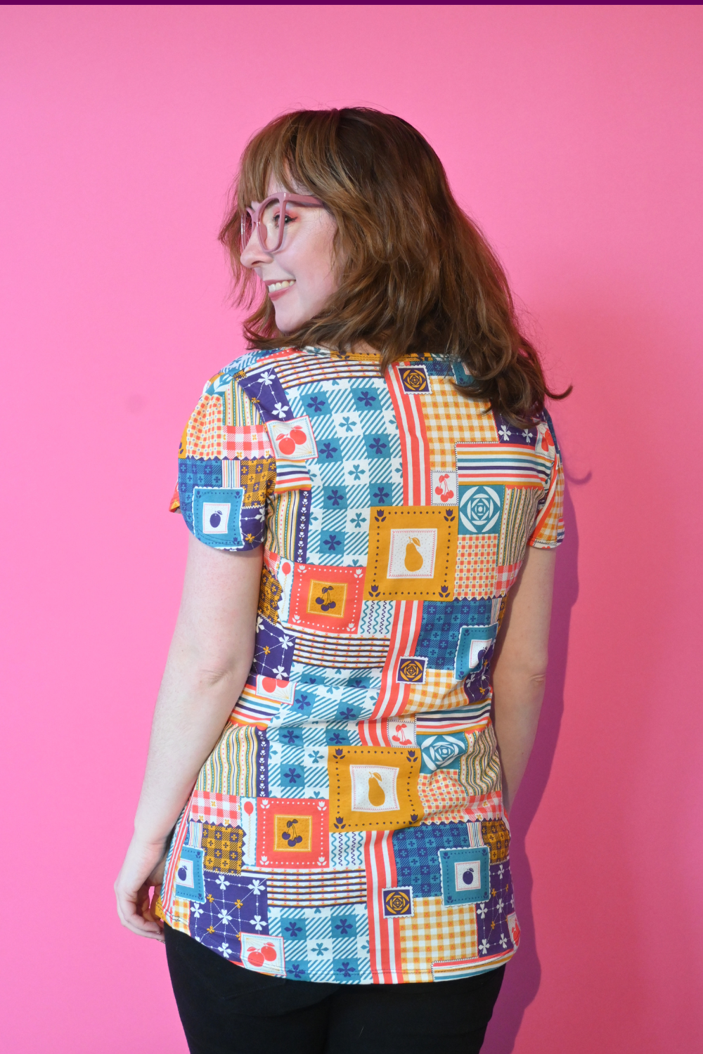 Pink-haired model in shirt printed with patchwork and fruit print