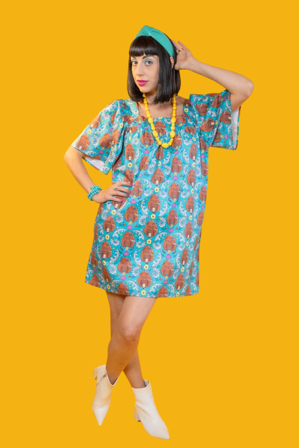 Model in short teal coconut monkey print dress and fun accessories