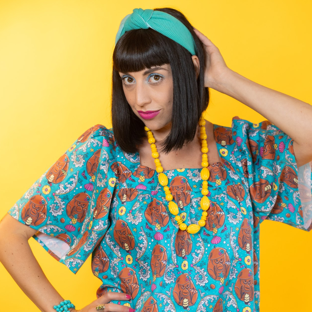 Closeup of model in short teal coconut monkey print dress and fun accessories