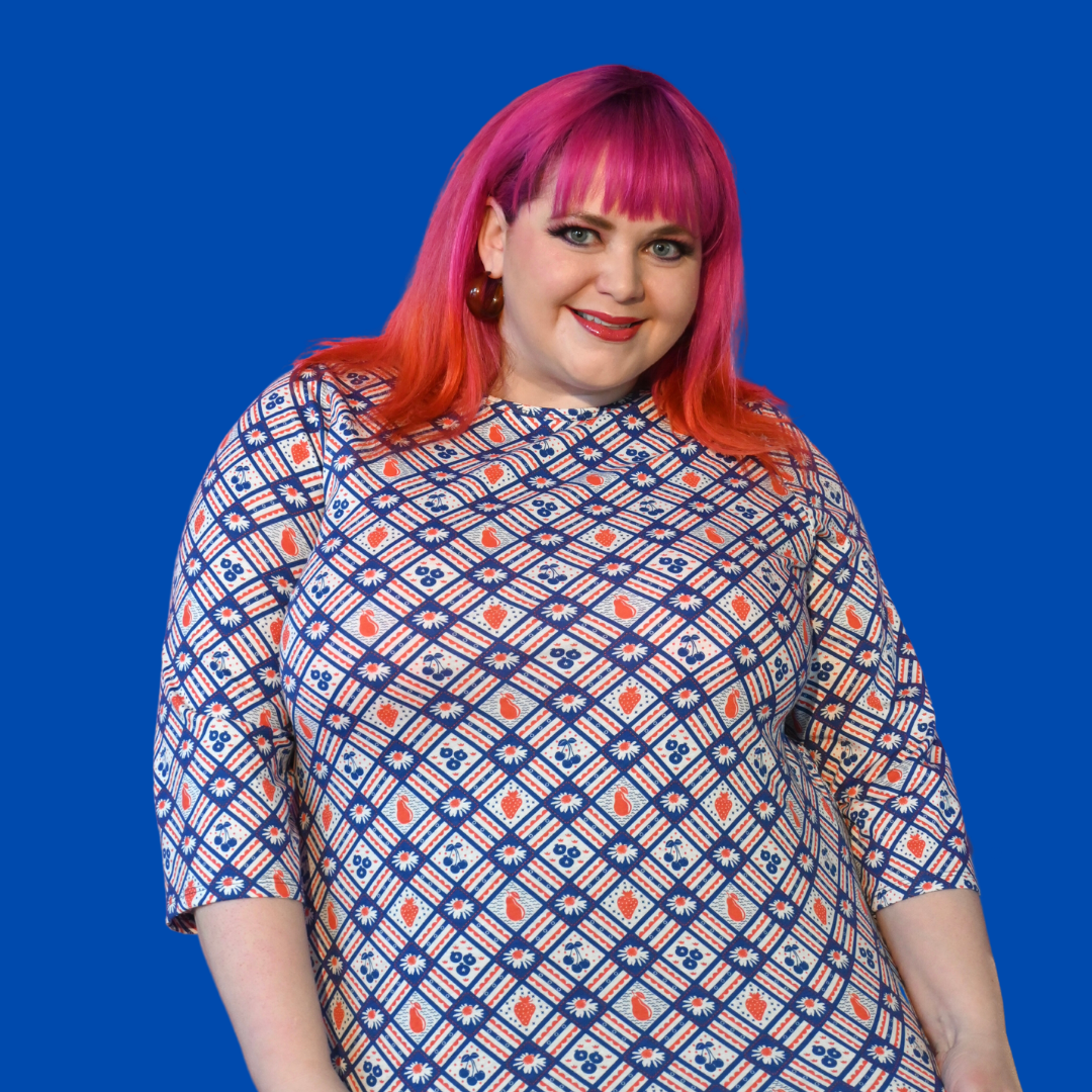 Pink-haired model wearing fruit print diagonal plaid graphic tee