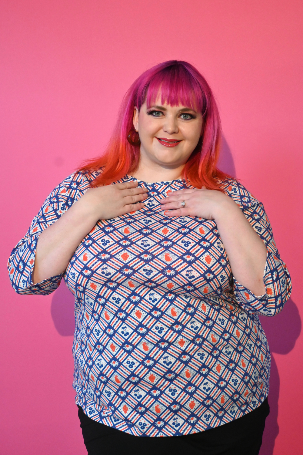 Pink-haired 2X model wearing fruit and flower print graphic tee