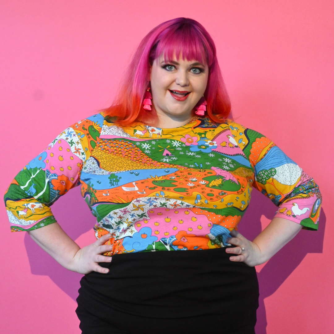 Pink-haired girl smiling in landscape print 3/4 sleeve tee in rainbow colors