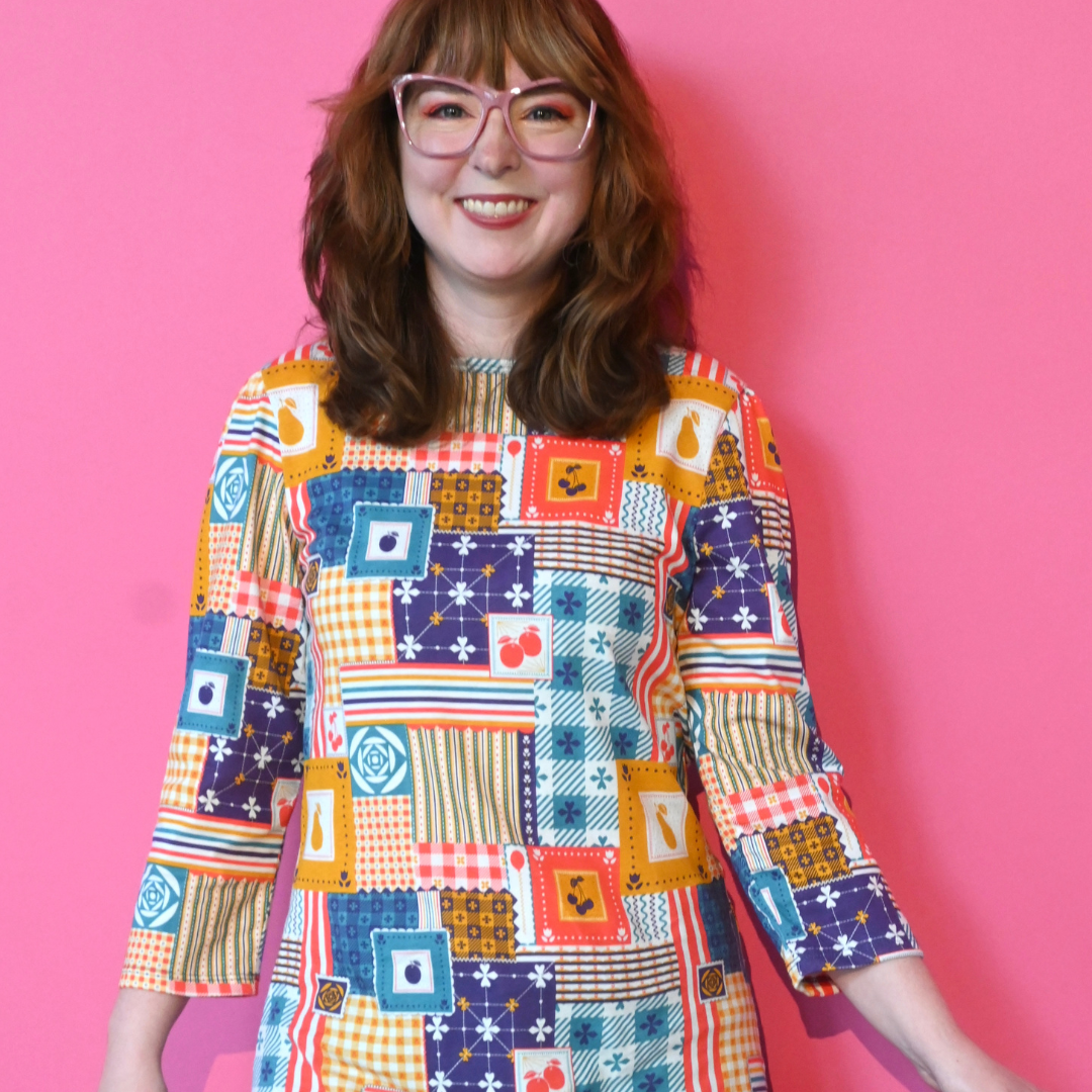 Redhead model in glasses wearing 3/4 sleeve tee featuring colorful patchwork