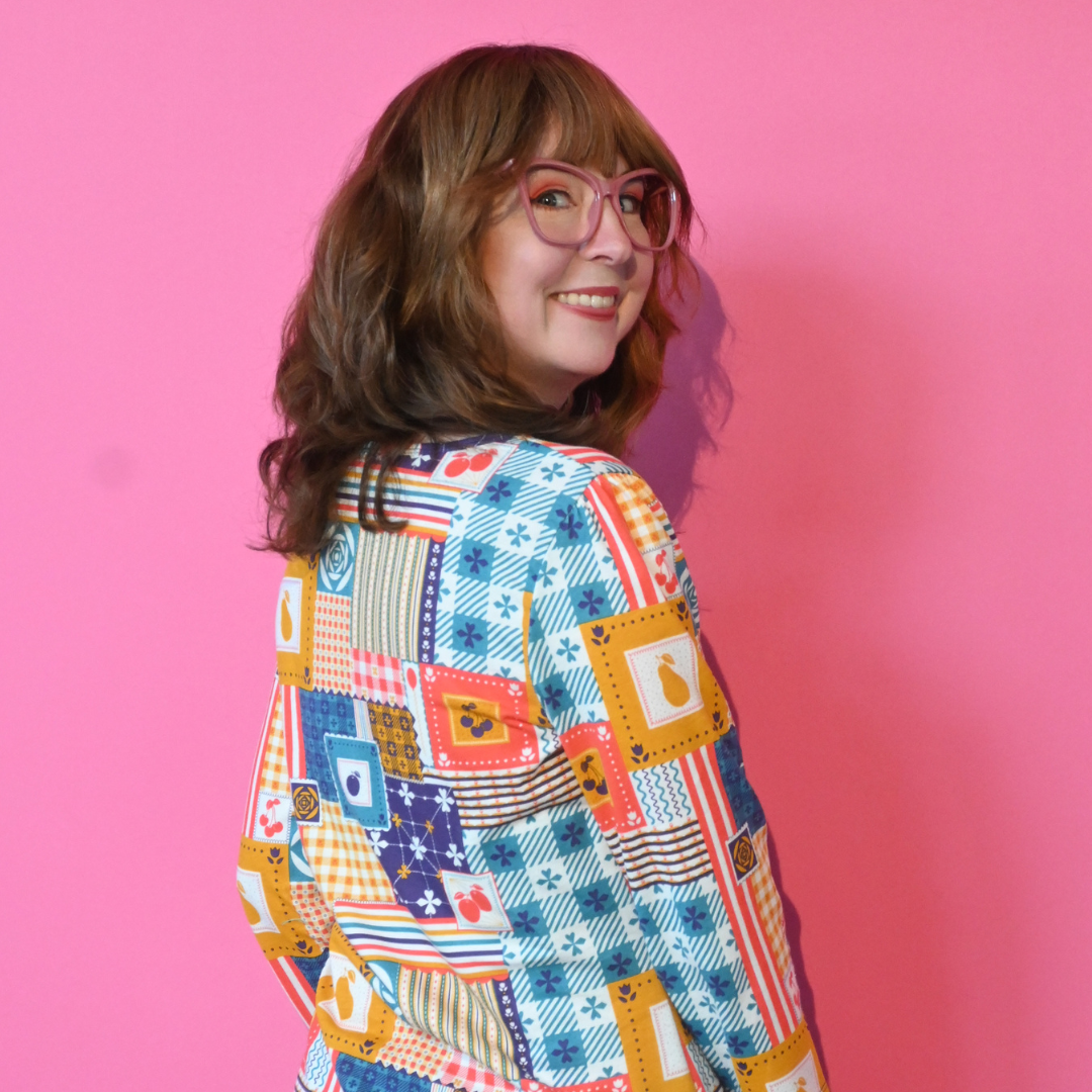 Back view of redhead model in glasses wearing 3/4 sleeve tee featuring colorful patchwork