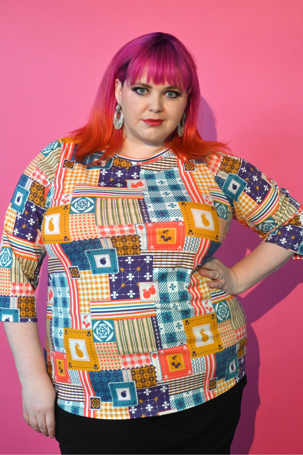 Pink haired model wearing 3/4 sleeve tee featuring colorful patchwork