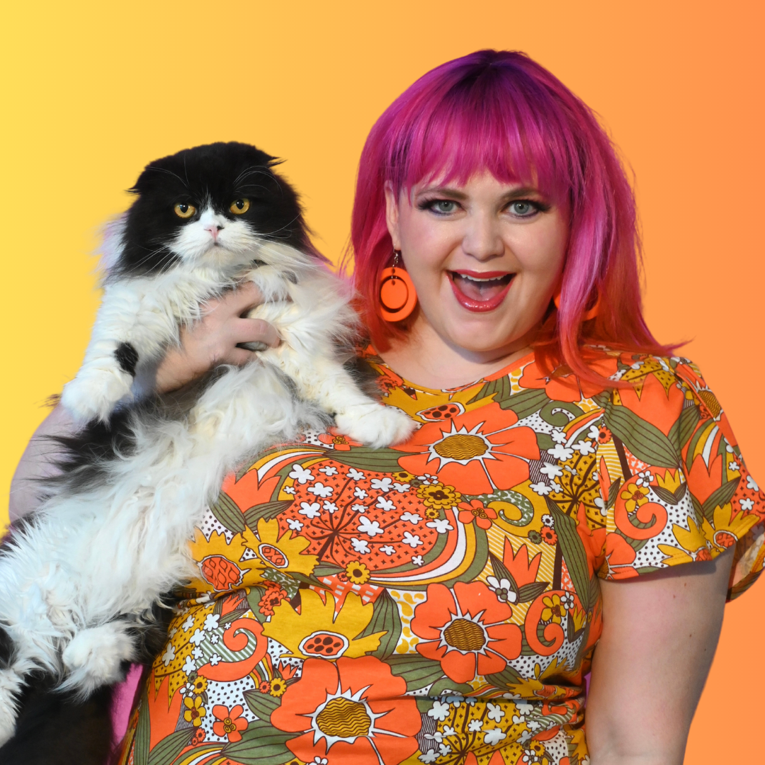 Pink-haired model holding cat and wearing floral print short-sleeved tee