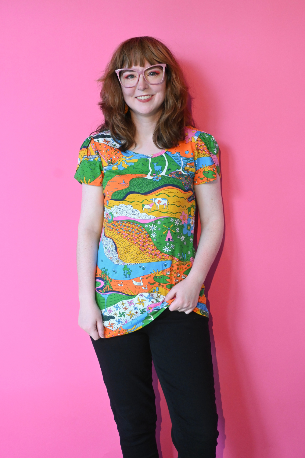 Model wearing glasses and shirt with landscape graphic in multicolor