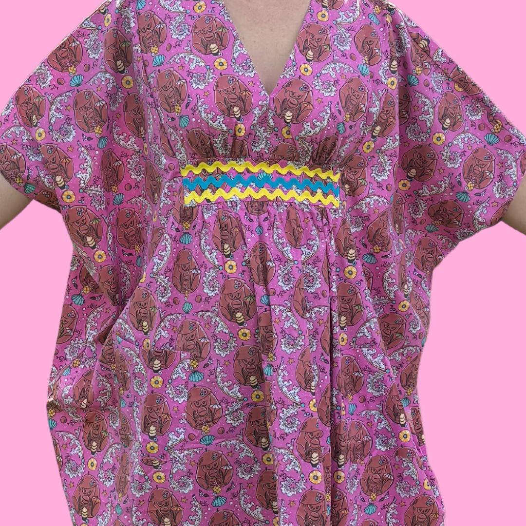 Closeup of pink monkey print caftan with ricrac trim