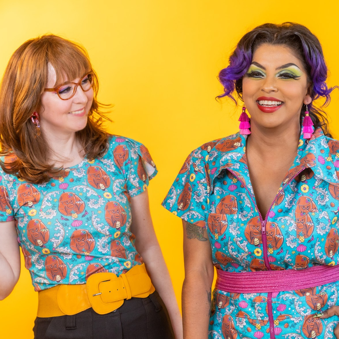 2 models laughing, in teal tiki print clothing