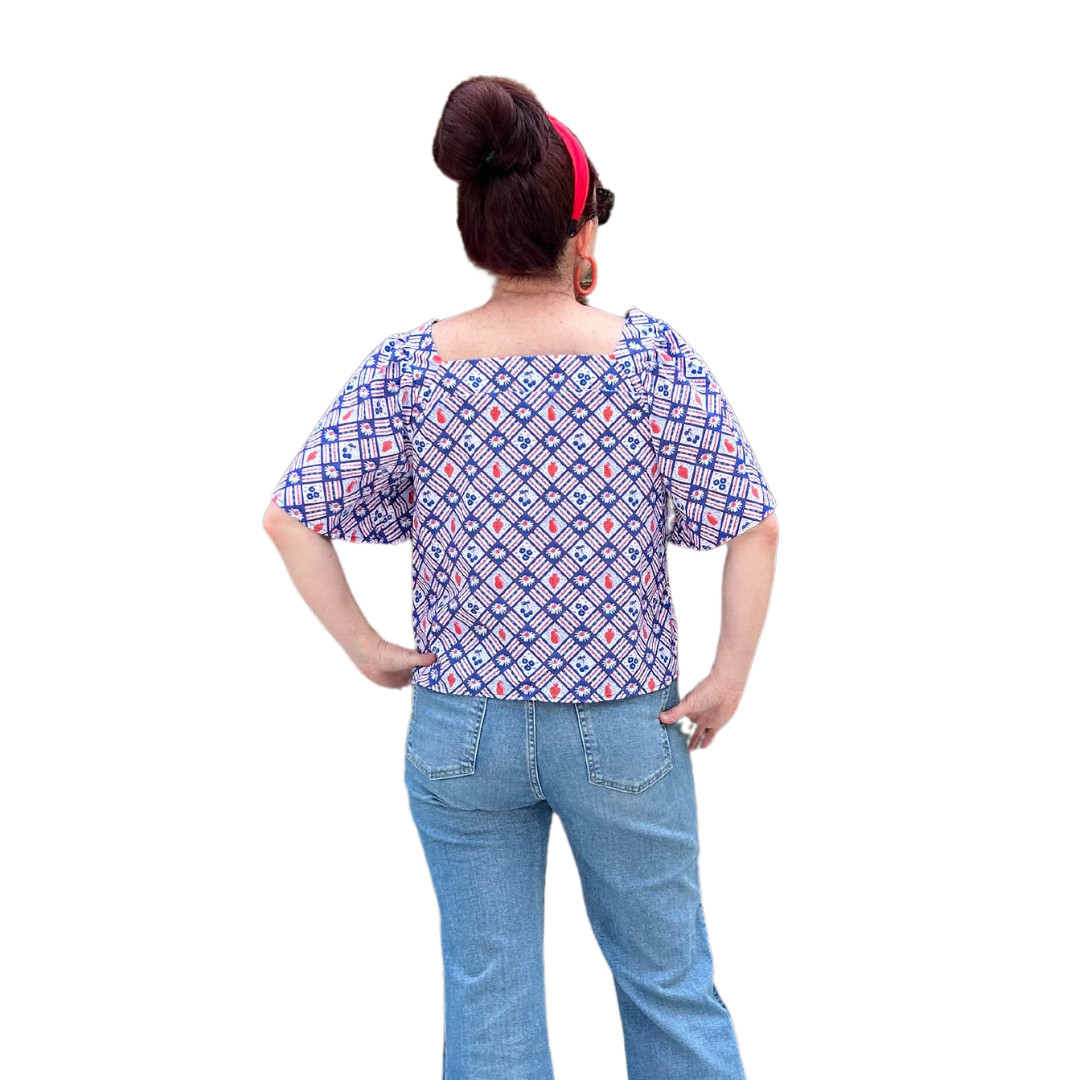 Back of square neck peasant top with blue and red print and graphic of fruit and flowers