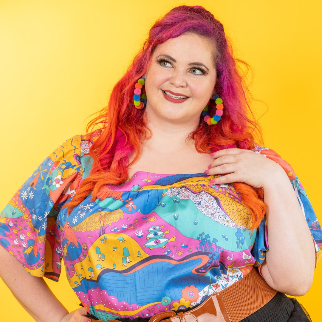 Pink haired model in bold earrings and colorful printed square neck top