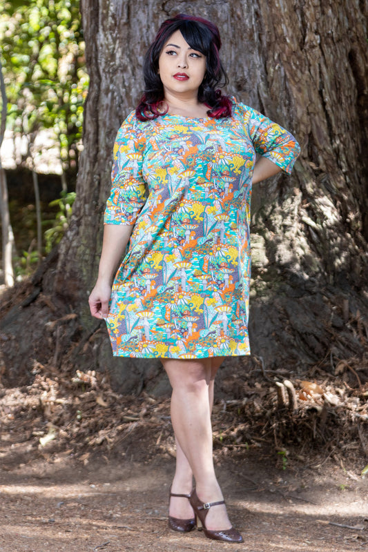 Model wearing teal, orange and yellow pocket tunic with mushrooms, flowers and snails