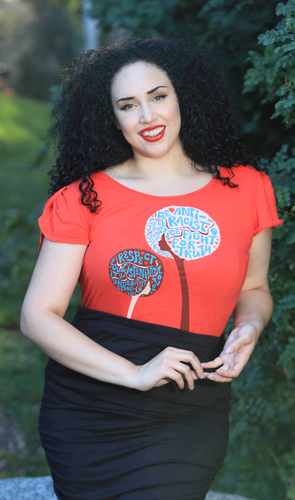 Curly-haired model with red shirt bearing anti-racist messages