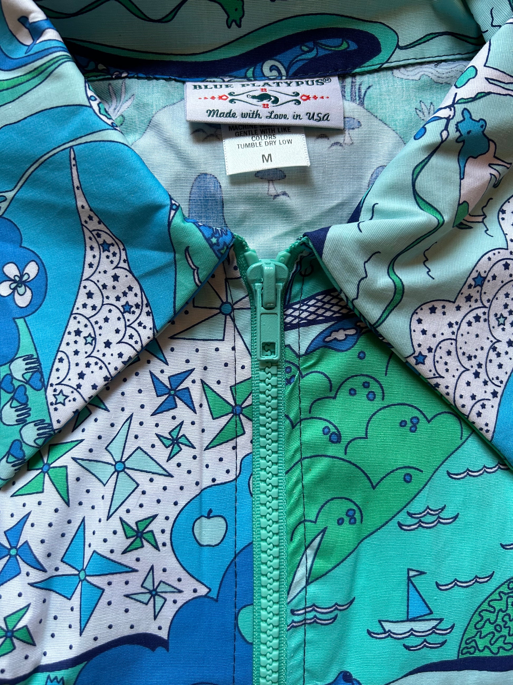 Closeup view of blue, white and green print featuring windmills, boats, and a cow