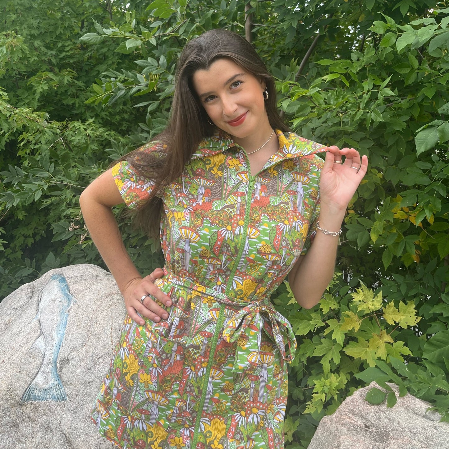 Dark-haired model in olive green, rust and mustard belted zip-front collared minidress