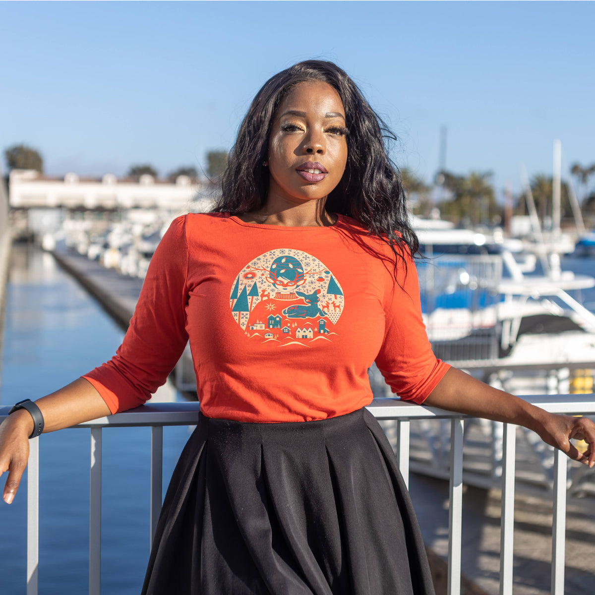 Bright red 3/4 sleeve Christmas tee with print of festive girl with beehive hair, reindeer, putz houses, snowflakes and pine trees