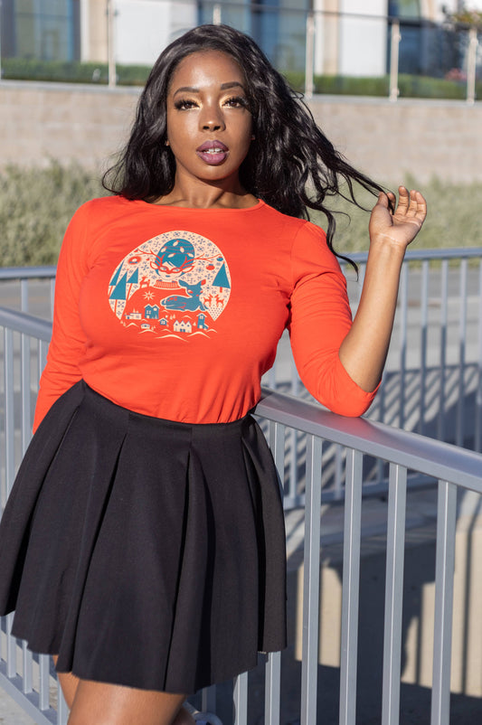 Long-haired model wearing bright red quirky Christmas tee with a black pleated skirt