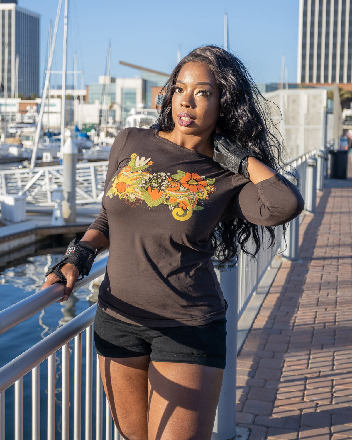 Dark-skinned model sunning herself in navy blue tulip-sleeved tee with bright floral print graphic