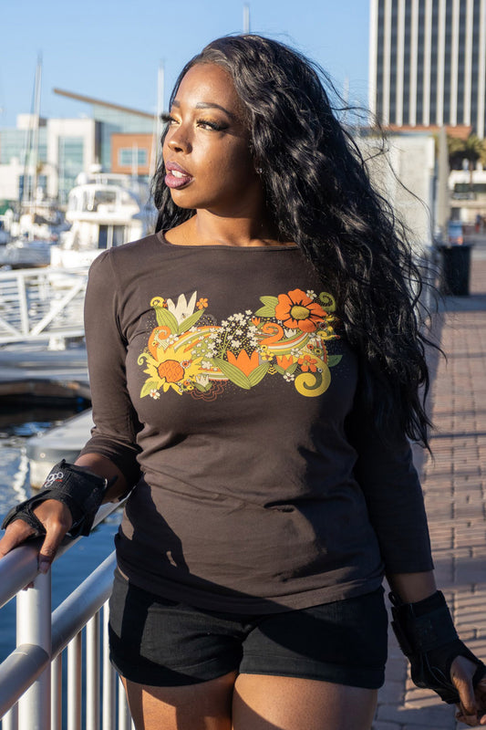 Dark brown tee with bright yellow, orange and green floral print on model at the beach