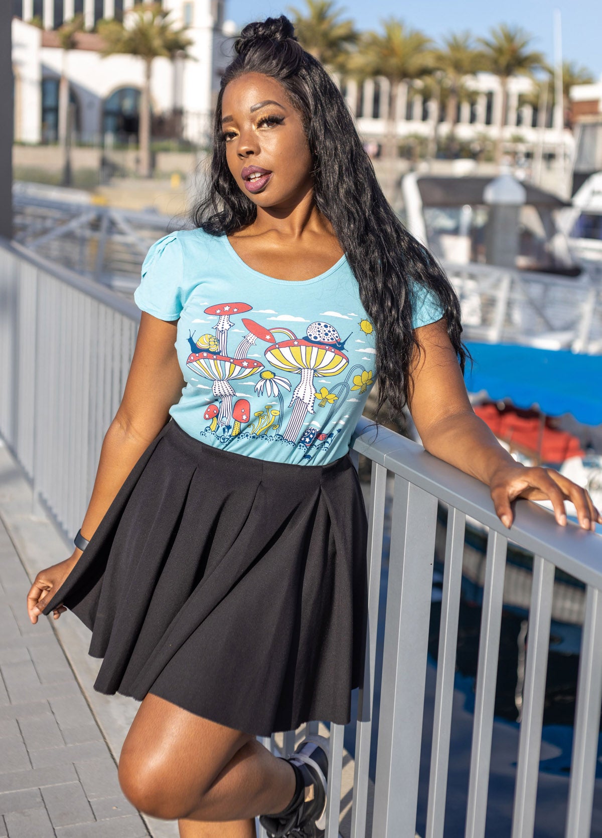 Sky blue tulip sleeve tee with mushroom, snail and flower graphic on dark skinned model, worn with black skirt